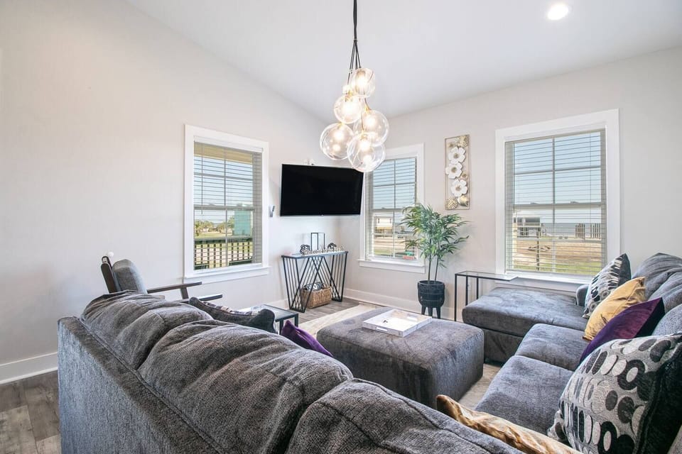 "Relax in Style: Modern Living Room with Comfy Sectional Sofa, Smart TV, and Breathtaking Beach View"