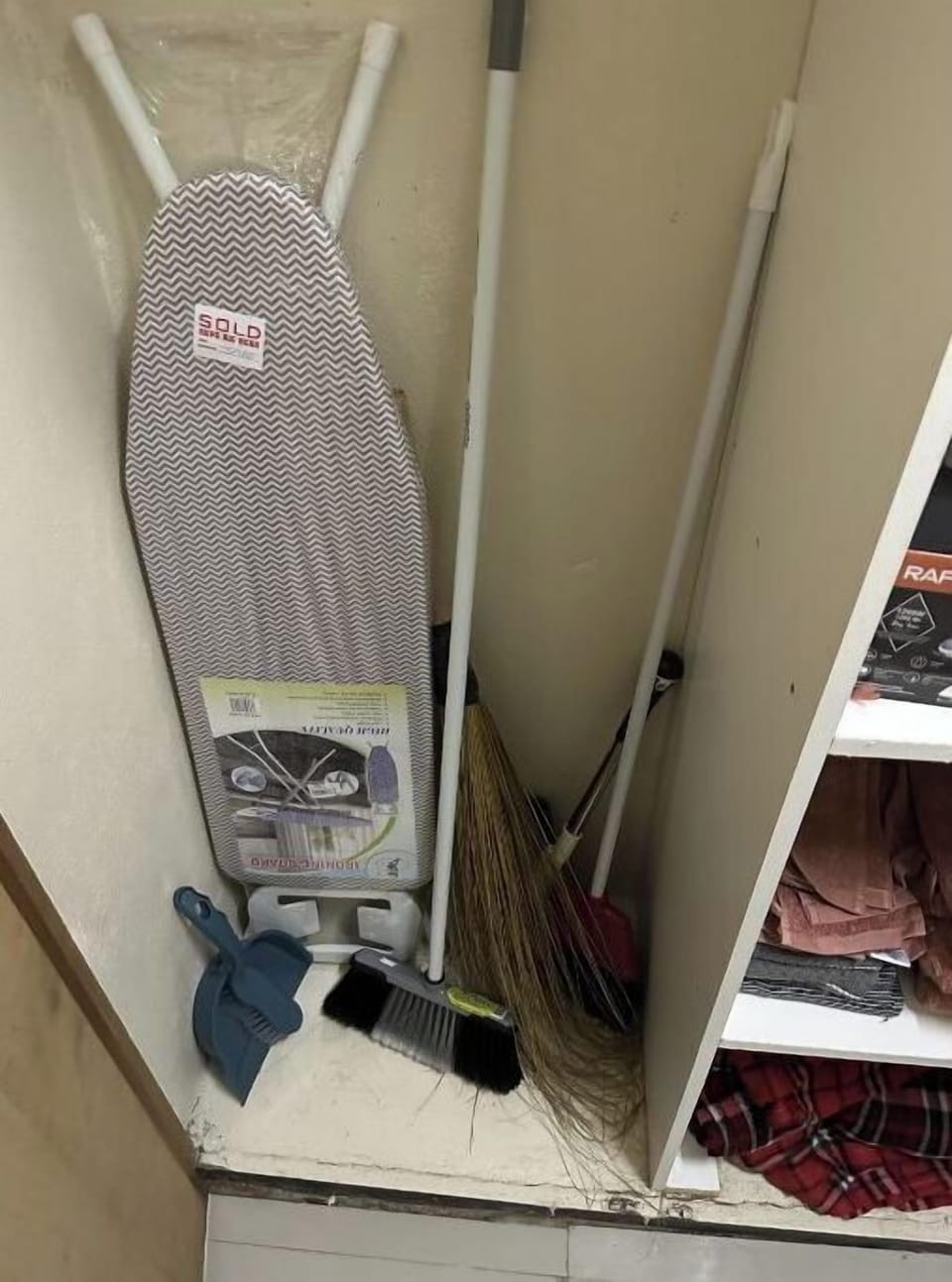 Ironing board, brooms and vacuum cleaner in hall closet.
