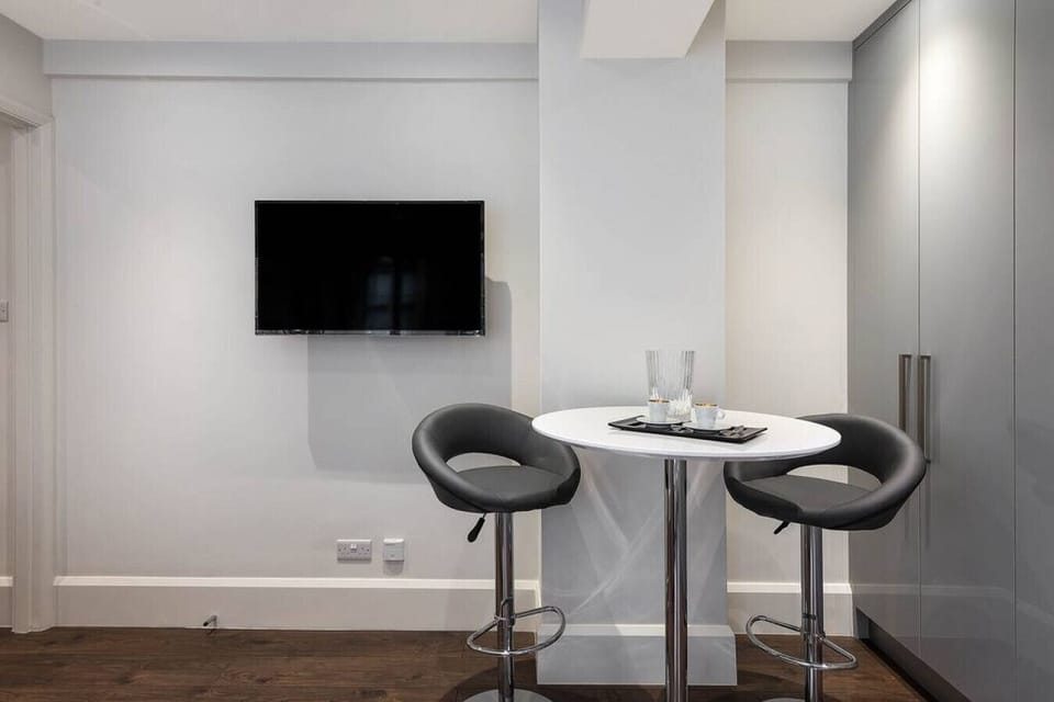 Living room — bar table and chairs alongside the large Smart TV with Netflix, Amazon Prime, and cable channels, set within the open-plan living space with hardwood flooring and bespoke cabinetry