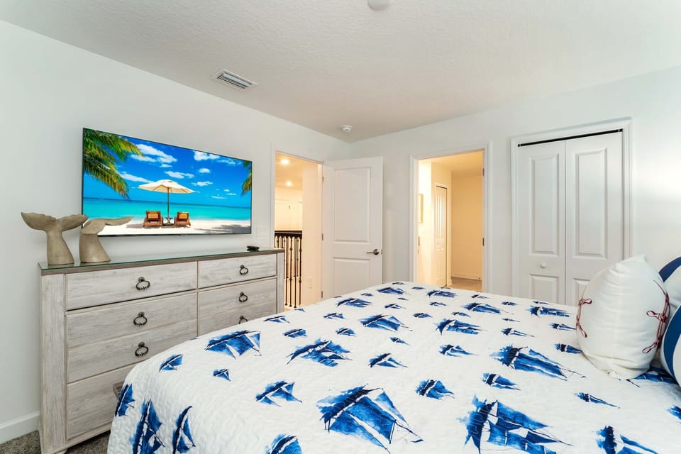 Relax in this nautical-themed bedroom with a large TV and stylish decor, perfect for unwinding after a day of adventure.