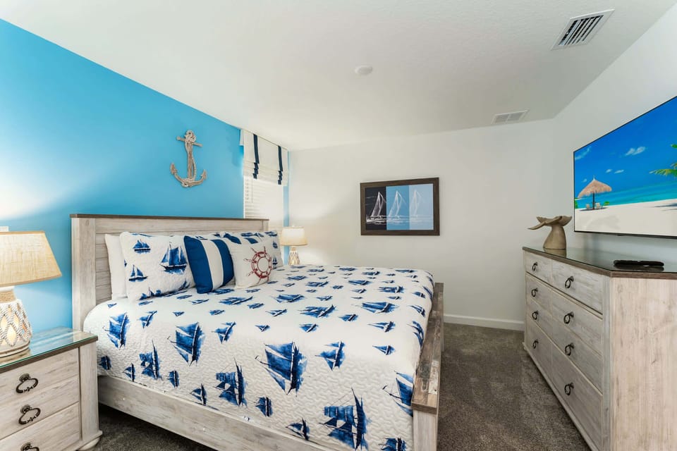 Relax in this nautical-themed bedroom with cozy bedding and a flat-screen TV, perfect for a seaside escape.