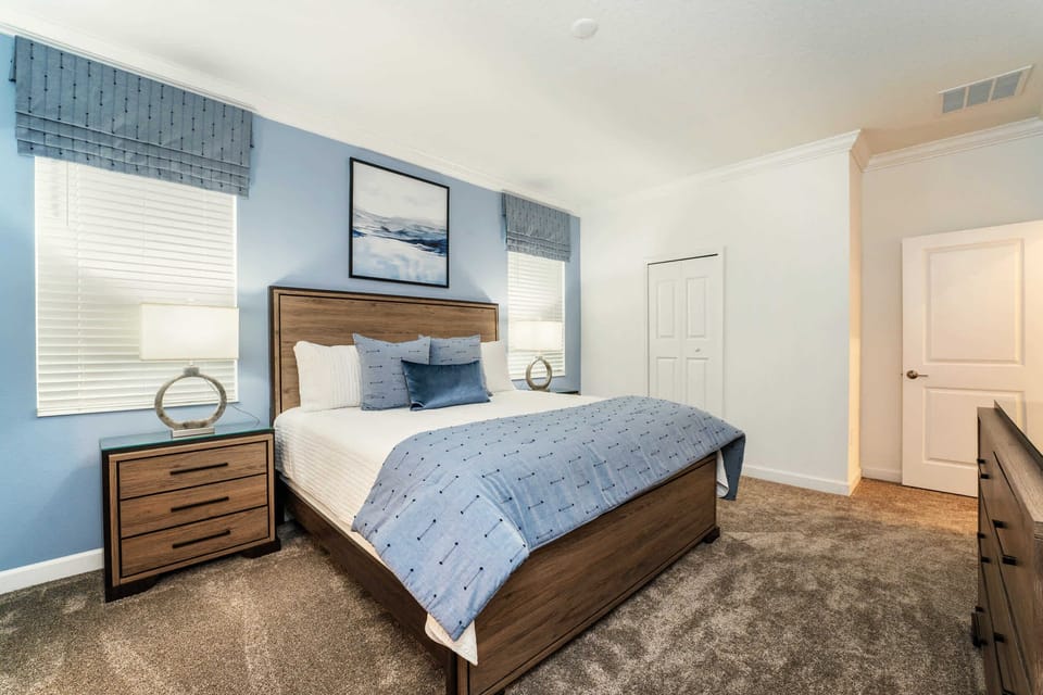 Relax in this serene bedroom with calming blue tones and plush bedding, ideal for a peaceful night's sleep.