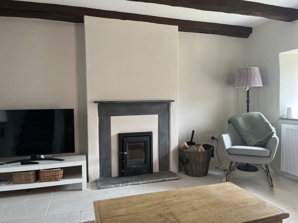 The sitting room with wood-burning stove and original  exposed beams