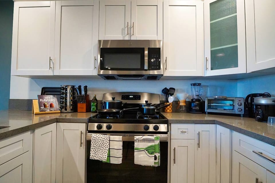 Full size kitchen complete with 15 piece cookware set.  Rice cooker/steamer, cutlery set, blender, toaster oven, chemex coffee maker, kettle, an array of spices, fridge/freezer, and gas range stove/oven.