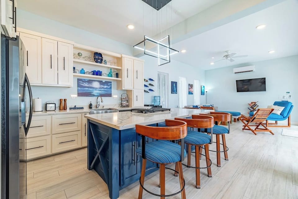 Open-concept kitchen and living area with breakfast bar, ocean-themed décor, and modern finishes on Ambergris Caye