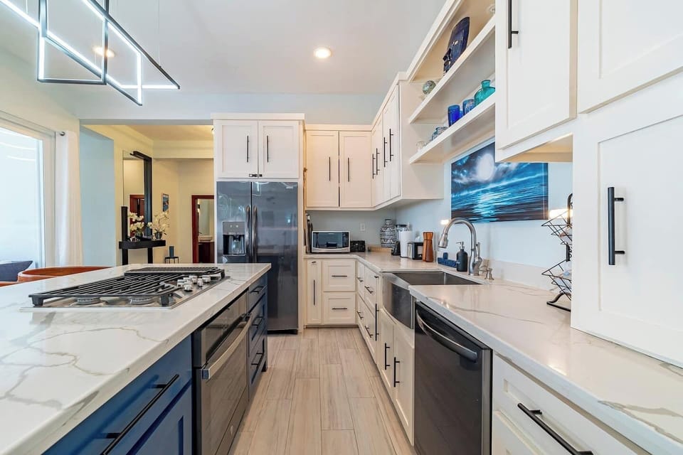 Chef’s kitchen with farmhouse sink, stainless steel appliances, gas stove, and custom cabinetry on Ambergris Caye