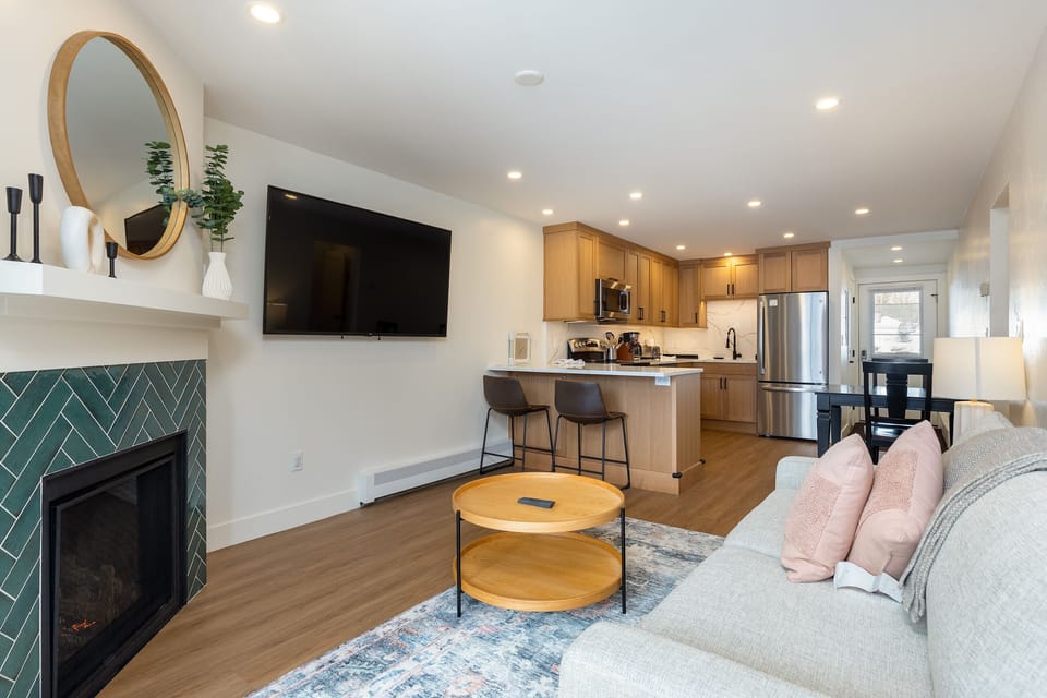 Relax in your bright, modern living space featuring a cozy fireplace, fully equipped kitchen, and stylish furnishings perfect for unwinding.