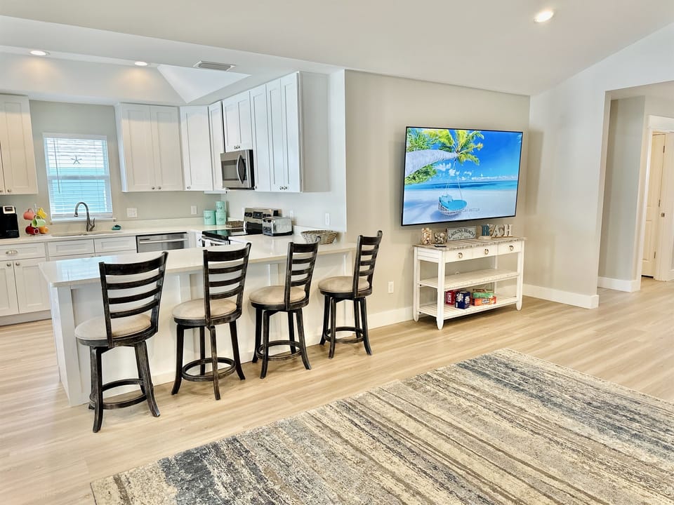 Open living room with comfortable seating and a 75' smart TV—perfect for relaxing after beach days.