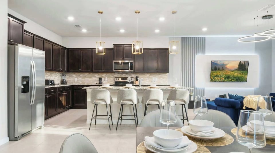 Chef’s kitchen with bar seating, designer lighting, and a cozy living room view.