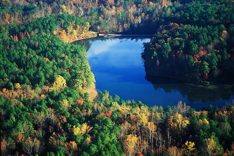 Explore a sweeping lake panorama surrounded by colorful forested hills.