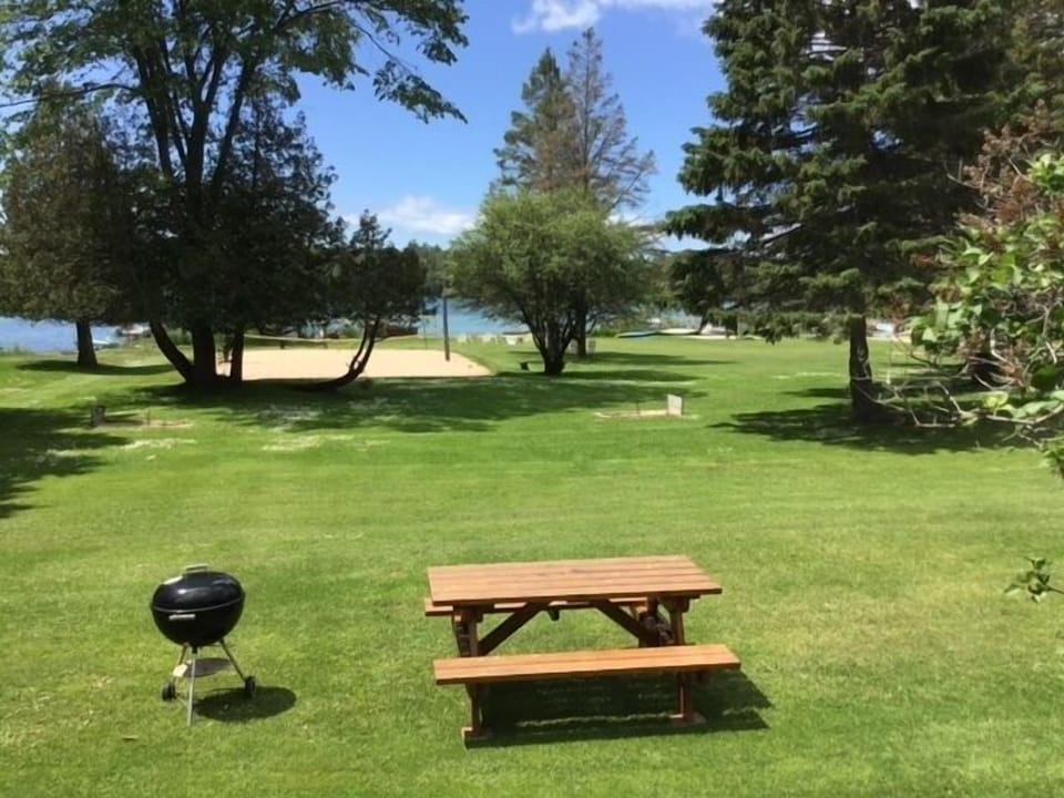 Coryell Cabin front porch view overlooking the sand volleyball court and channel