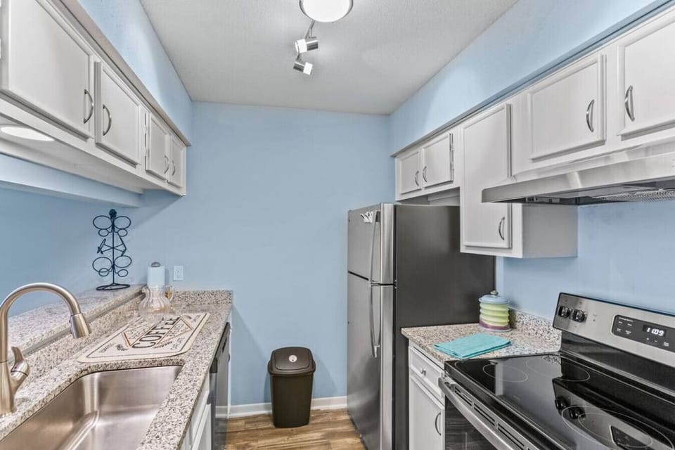 Hallway view of the kitchen with sink, oven, ref and  cabinets
