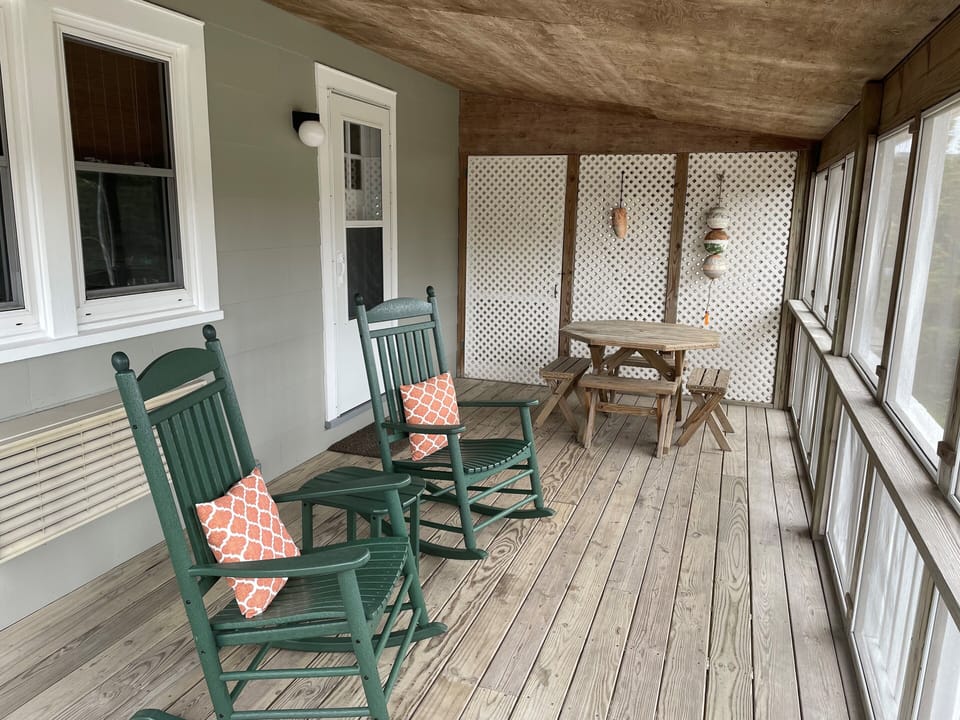 Two rocking chairs and a picnic table on the screened porch