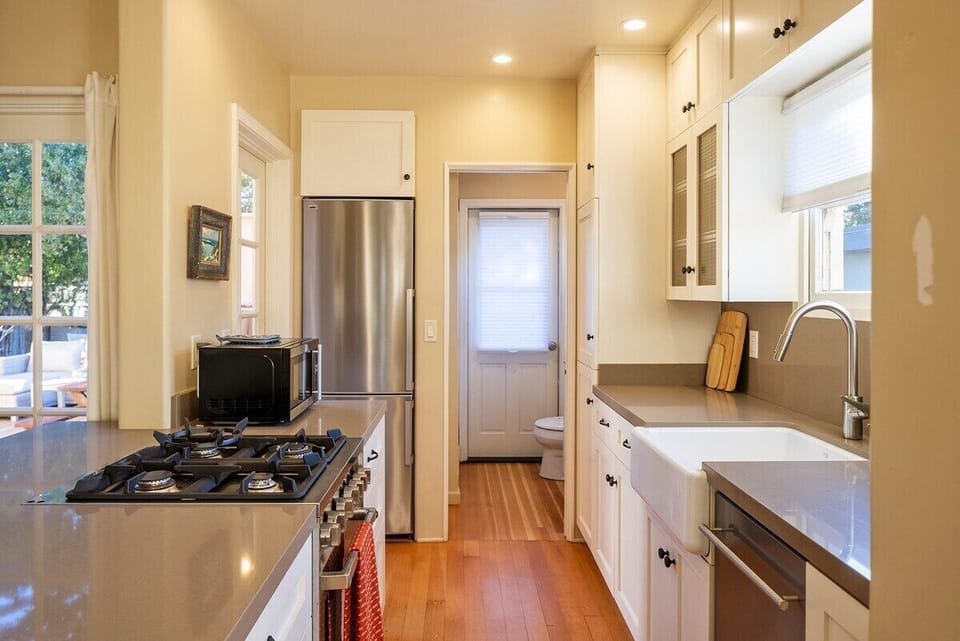Kitchen with gas range, dishwasher, microwave, coffee makers. 2nd full bath off of kitchen with shower and door to bbq patio.