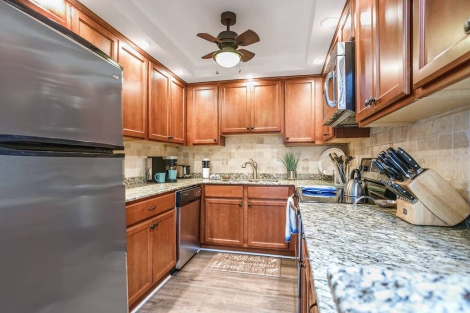 Solid stone counters and stainless appliances with plenty of plates, dishes and stemware