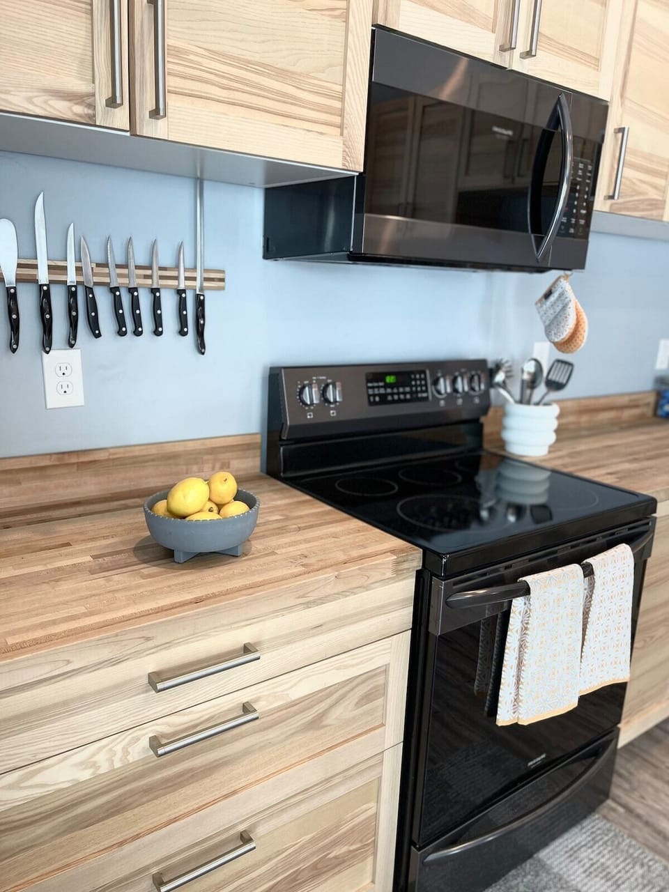 Stocked kitchen with electric stove/oven, microwave, bakeware, toaster, Rachel Ray pots and pans, and basic kitchen utensils.