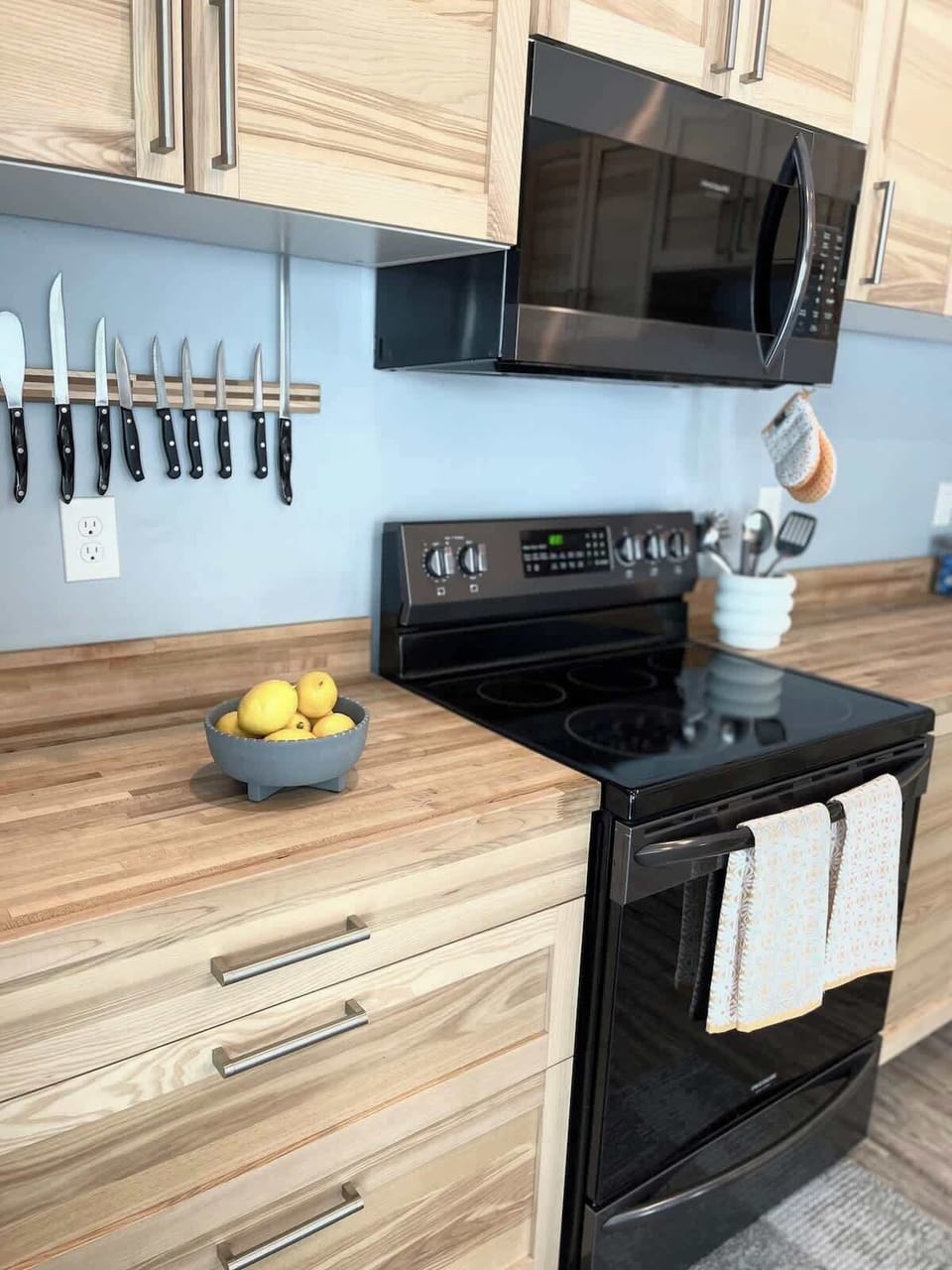 Stocked kitchen with electric stove/oven, microwave, bakeware, toaster, Rachel Ray pots and pans, and basic kitchen utensils.