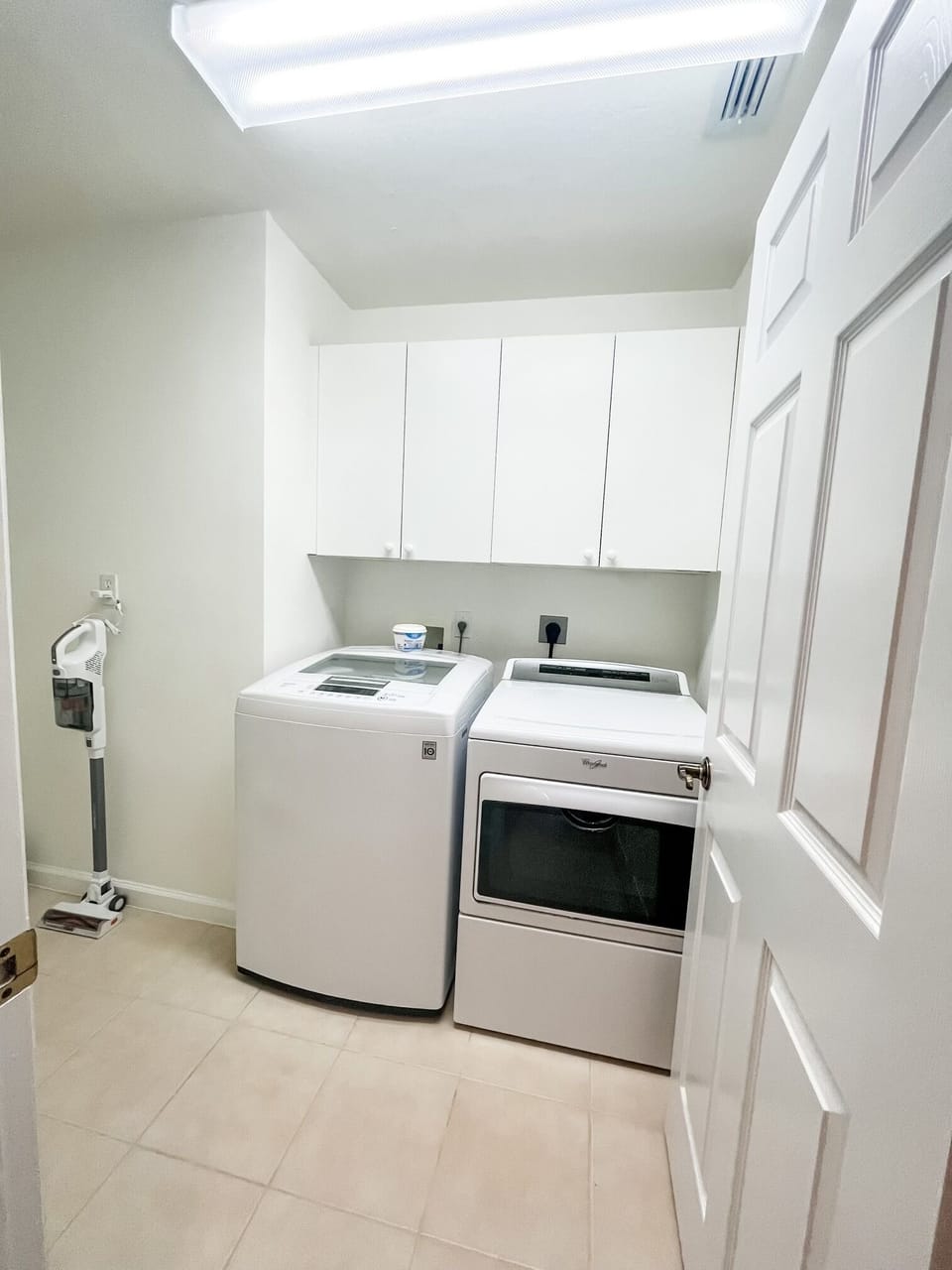 An in-unit laundry area with a washer, dryer, and spacious cabinets.
