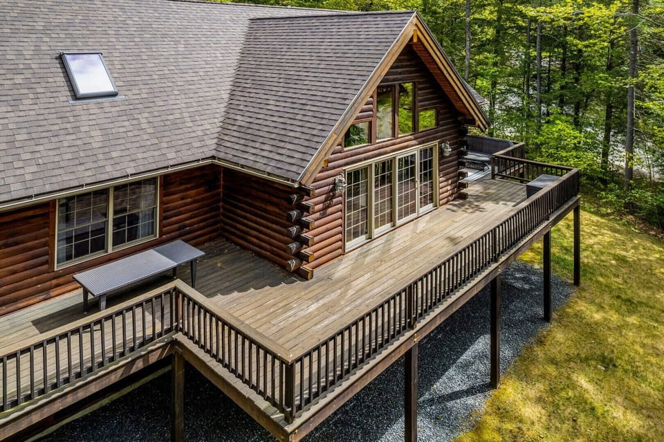 Wraparound upper deck with outdoor dining
    table — drone view showing the private
    wooded lot
