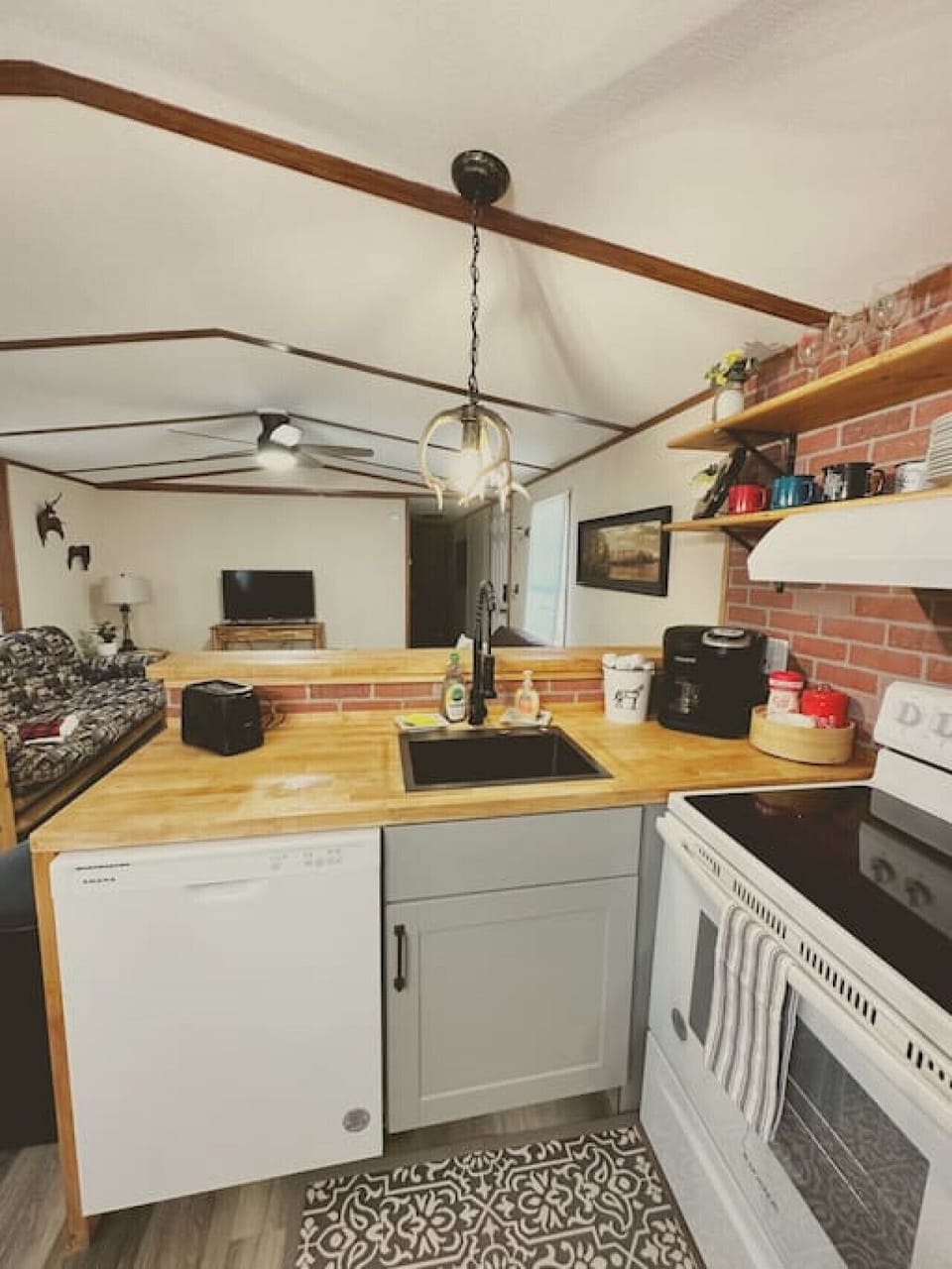 Fully stocked with all your cooking and dining essentials, this kitchen boasts exposed shelving, a dishwasher, microwave, and a Keurig & drip coffee maker combo—with coffee included!