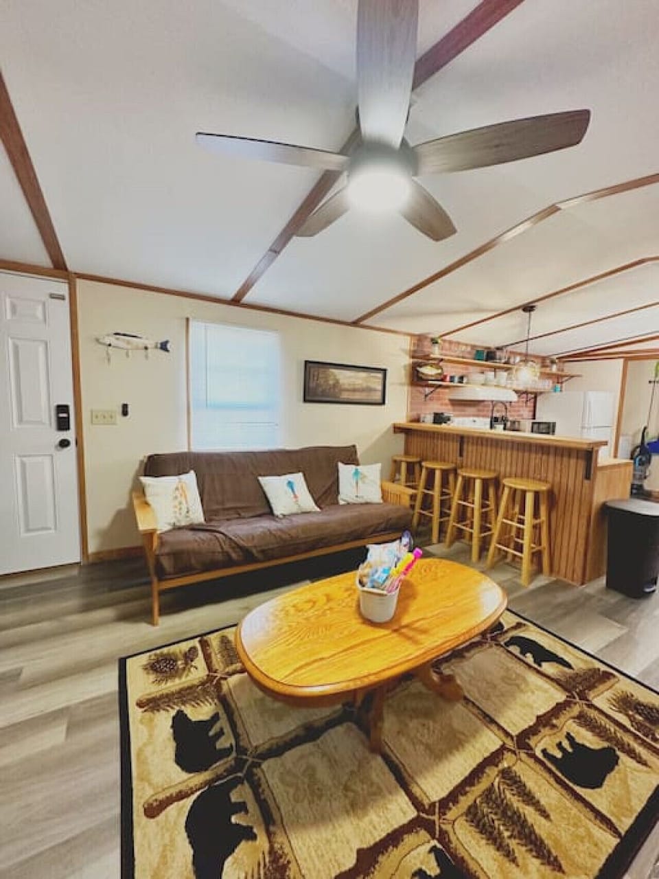 Relax in a spacious living area featuring two full-size futons, a ceiling fan, a large coffee table, and a Roku streaming TV. Conveniently adjacent to the kitchen for easy entertaining!