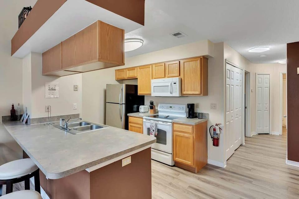 Open kitchen with wooden cabinets and a breakfast bar for casual dining.