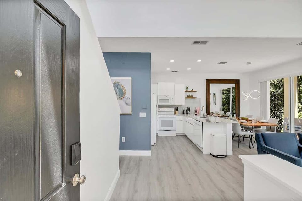 Open-concept kitchen and dining area with modern white cabinetry and natural light.