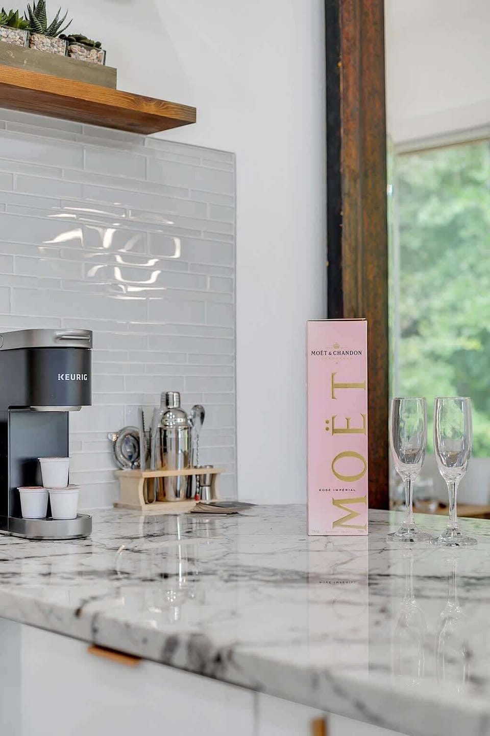 Modern kitchen counter with a keurig coffee maker and champagne setup for a relaxing moment.