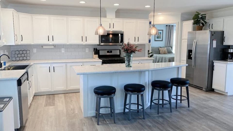 Large kitchen with new whirlpool appliances and four barstools.