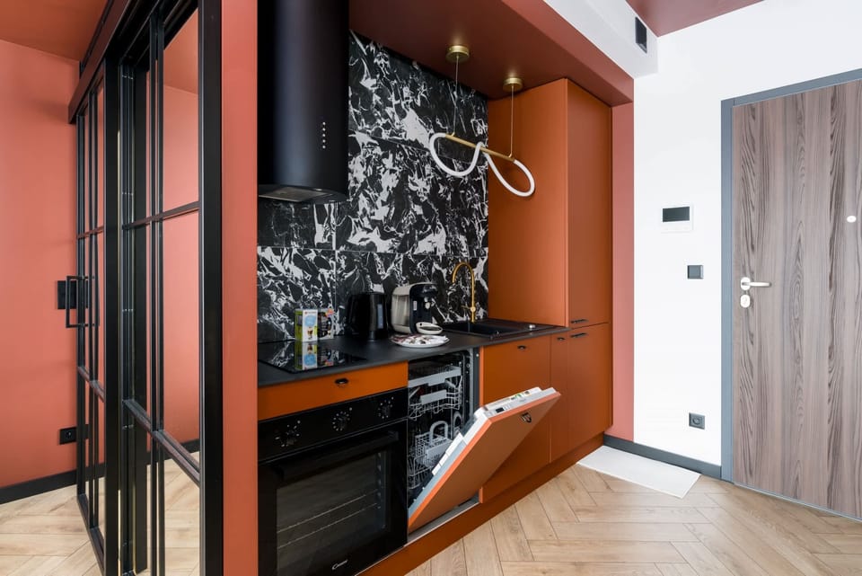 A small kitchen corner with a coffee machine and black cabinetry, offering a sleek design.
