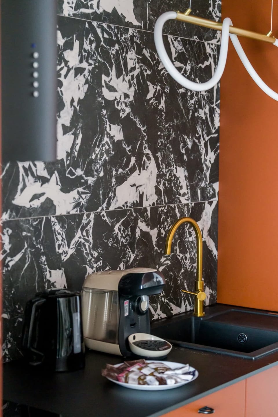 A small kitchen corner with a coffee machine and black cabinetry, offering a sleek design.

