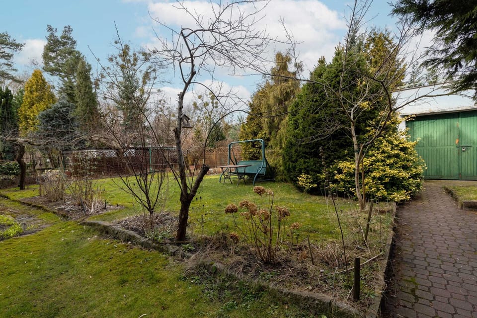 An expansive garden with neatly arranged flower beds, trees, and a tranquil atmosphere.





