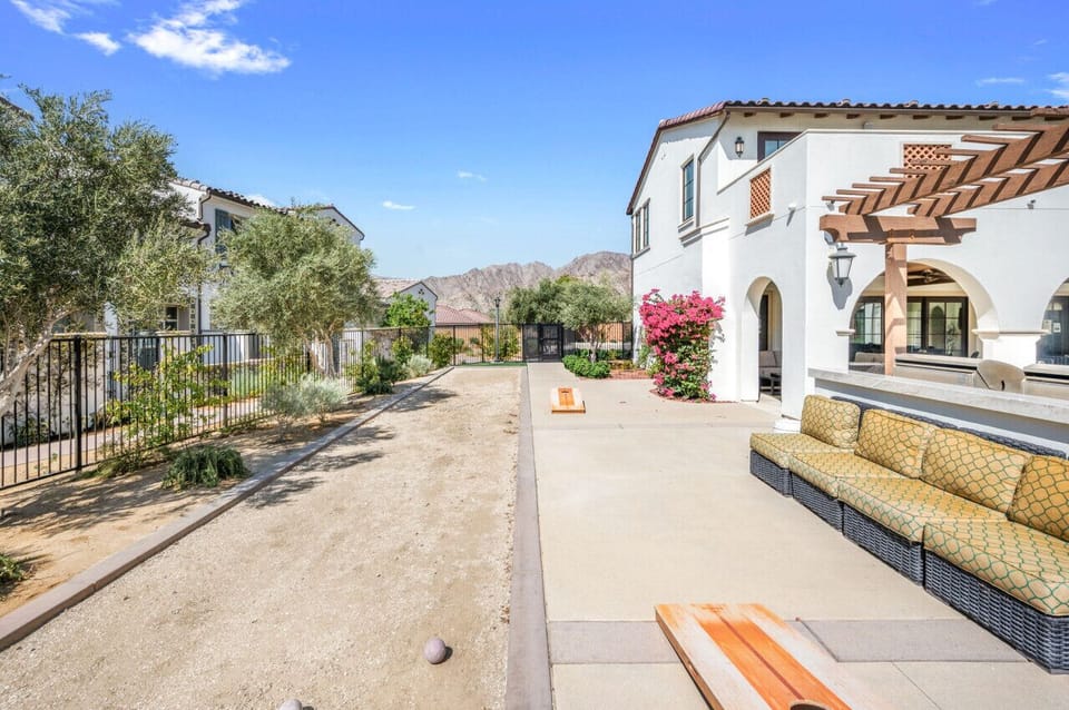 Peaceful neighborhood street lined w/ homes & desert landscaping under blue skies