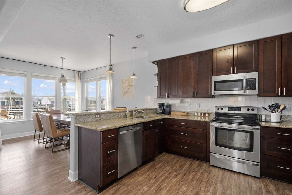 Fully equipped kitchen with stainless steel appliances, granite island, dishwasher, microwave, range, and breakfast seating.