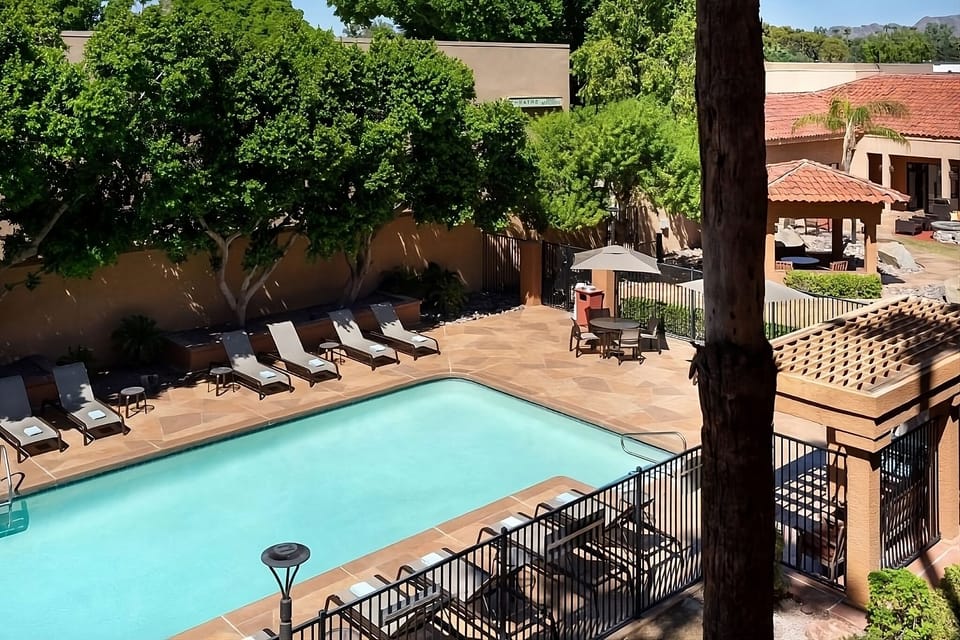 Sip something cold while relaxing poolside under leafy trees.