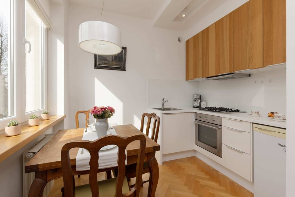 A bright kitchen with wooden cabinets, a dining table, and a view of the garden outside.
