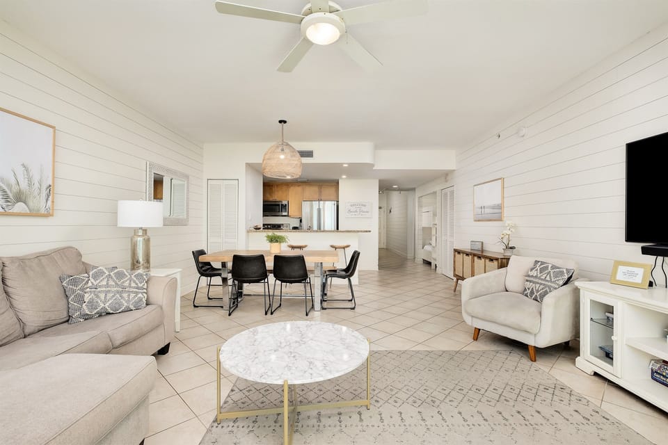 Relax in your bright open-plan living space with shiplap walls, modern furnishings, and a ceiling fan keeping you comfortable.