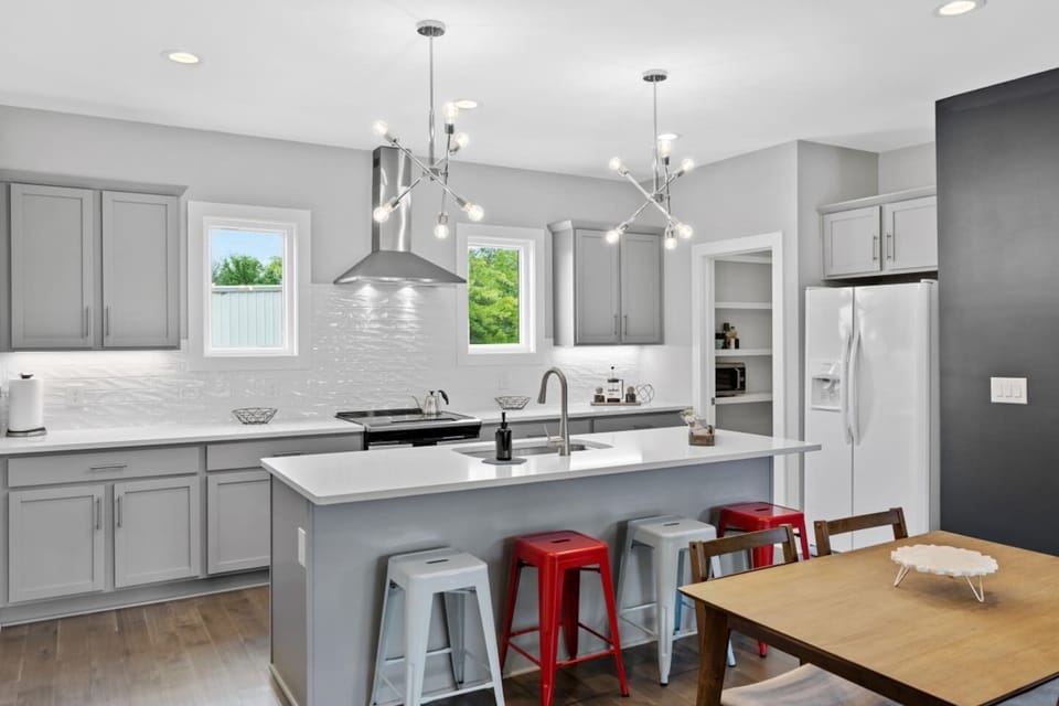 Fully equipped kitchen with stainless steel appliances, a large central island, and modern pendant lighting—ideal for cooking brunch or hosting pre-game drinks