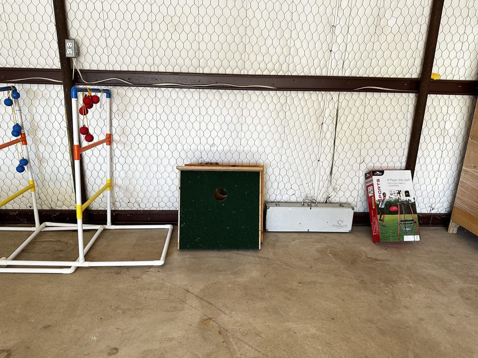 Outdoor barn has ping pong table, ladder golf, and corn hole as well as a paddle board.