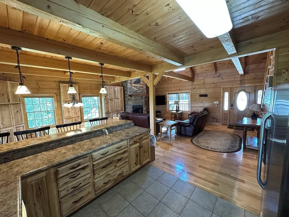 The kitchen has a large L-shaped countertop with lots of seating space for high-back chairs, lots of cabinet space, and a huge amount of cabinet storage space in the back behind the dining table against the back wall. 