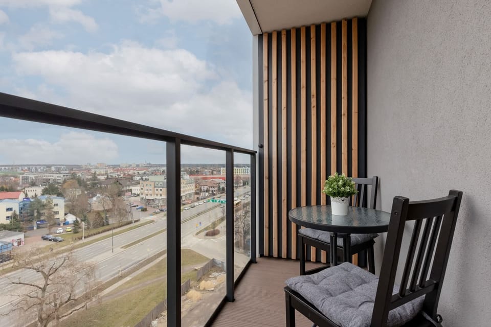 A balcony with a small table and chairs, offering views of the surrounding area.
