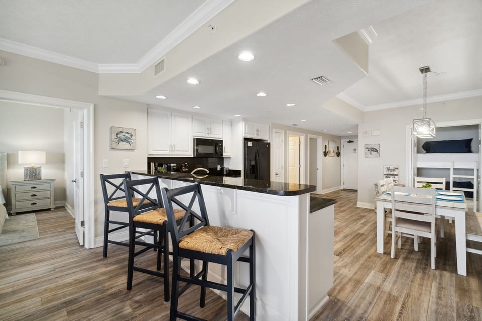 Modern kitchen with black countertops and bar seating overlooking the dining area.
