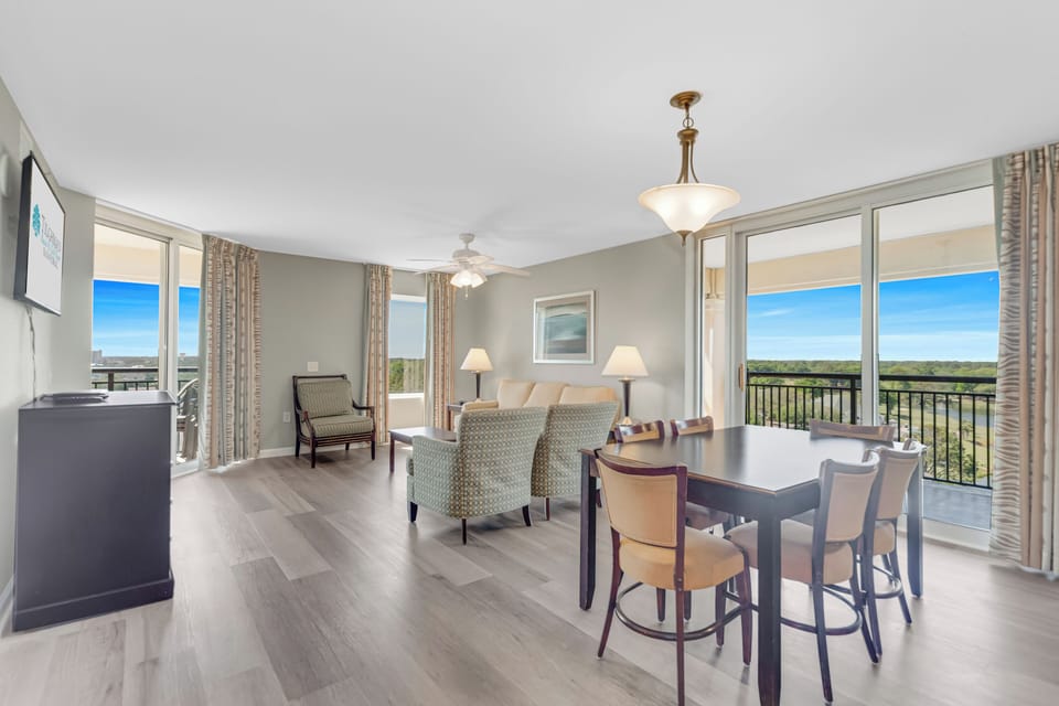 Relax in your bright, elegant living space with panoramic windows framing stunning views and a stylish dining area perfect for memorable meals.