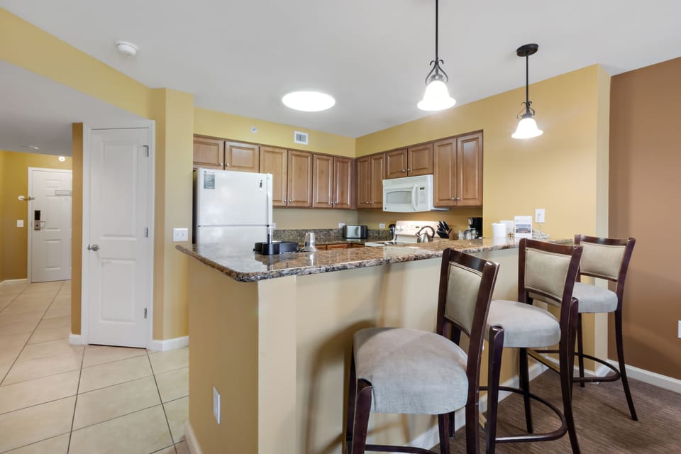 Your fully-equipped kitchen features granite countertops, warm wood cabinets, and stylish bar seating perfect for morning coffee or casual meals.