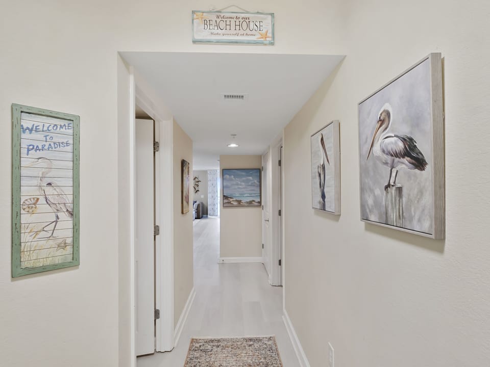 Step into your coastal retreat where welcoming beach-themed artwork and soft lighting create a warm first impression in this beautifully appointed hallway.
