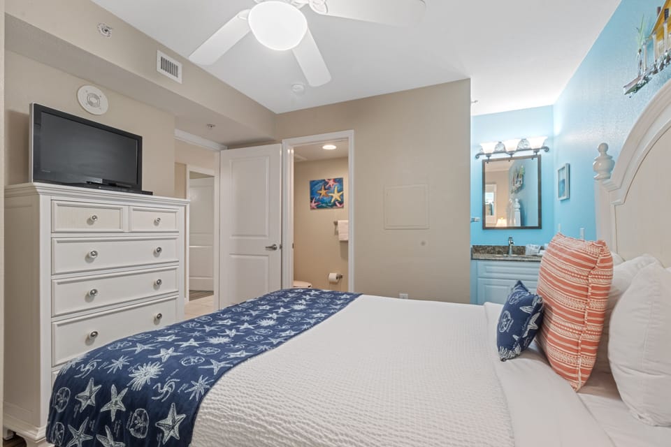 Relax in your coastal-themed bedroom with nautical accents, white linens, and convenient entertainment setup for peaceful nights.