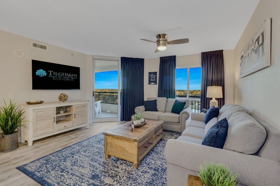 Relax in your spacious living room with plush seating, scenic balcony views, and modern entertainment setup.