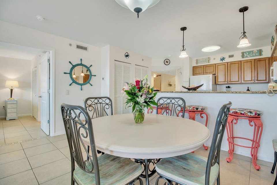 Your coastal dining space features nautical charm with colorful seating and an open kitchen perfect for memorable meal gatherings.