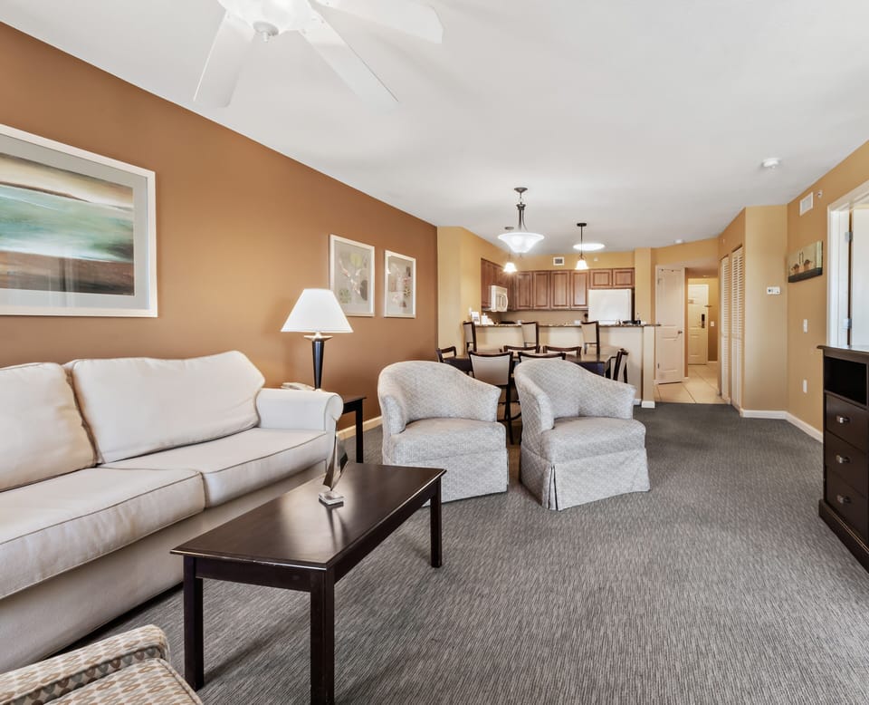 Unwind in your spacious living room with plush seating and warm earth tones, flowing seamlessly into your fully equipped kitchen.
