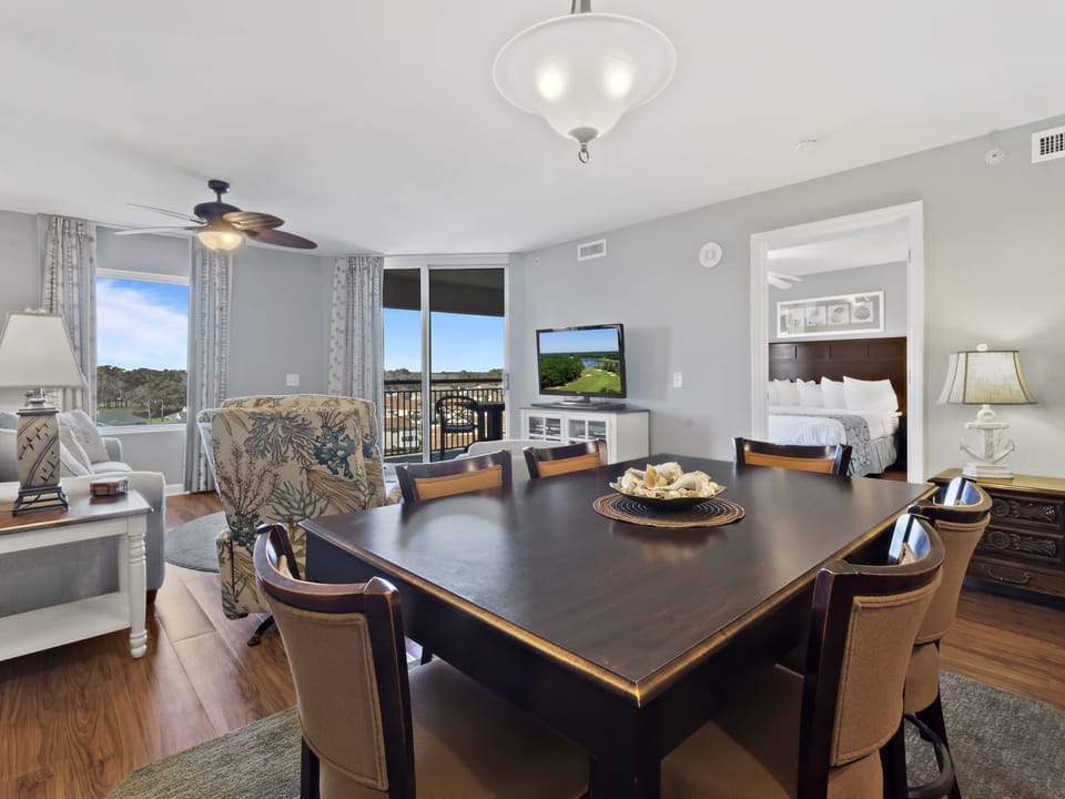 Your elegant dining space features a spacious table for eight, with natural light streaming through floor-to-ceiling windows overlooking scenic views.